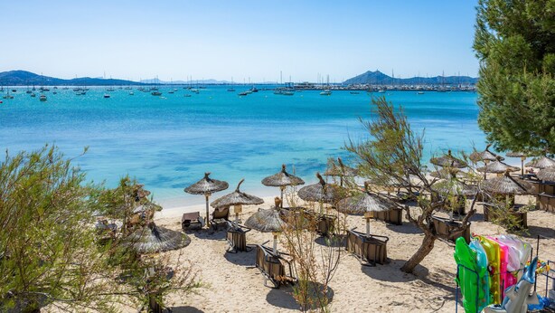 A beach with thatched umbrellas, a sandy shore, and boats in the water. - Apartment 'Voramar 33A Joana Duplex' with Sea View, Private Terrace and Wi-Fi (Port Pollensa)