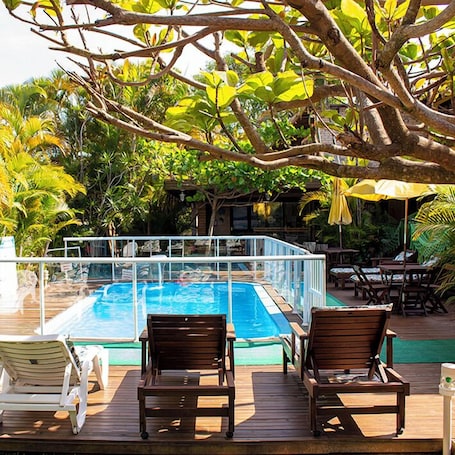 Una piscina al aire libre, sillones reclinables de piscina