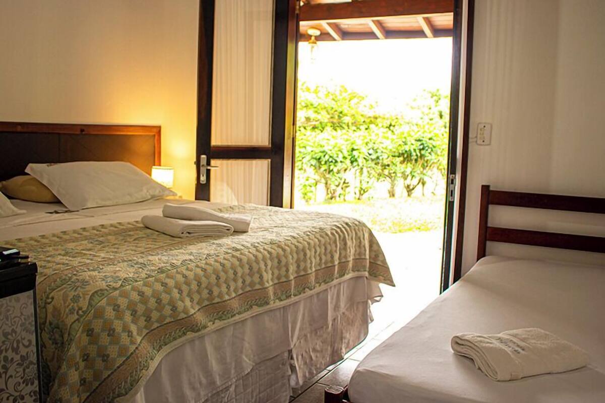 A hotel room with a bed, a nightstand, and a window with curtains.