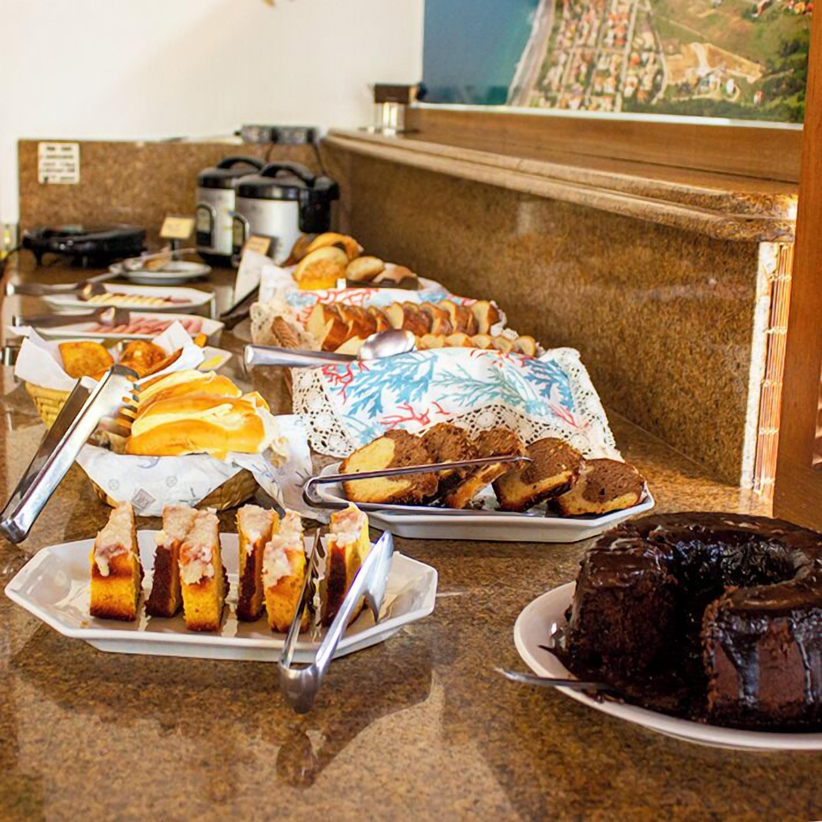 A buffet with various food items including pastries, sandwiches, and a chocolate cake.