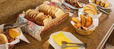 A buffet with various food items including bread, pastries, and meats.
