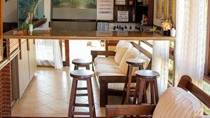 Eine gemütliche Bar mit einer Holztheke, Barhocker und einer Wandmalerei mit einer Küstenansicht.
