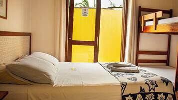 Una habitación de hotel con una cama, un ventanal con vista a un edificio amarillo y una litera.