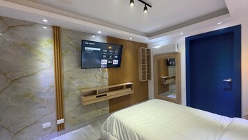 Un dormitorio moderno con una cama grande, un televisor montado y un panel de pared de madera.