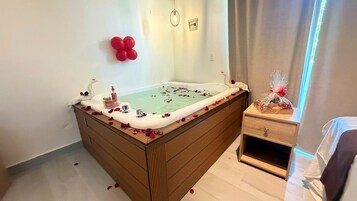 Un baño con bañera, armario de madera y una mesita de noche.