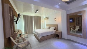 Une chambre d’hôtel moderne avec un grand lit, un bureau avec une chaise, une télévision et un grand miroir.