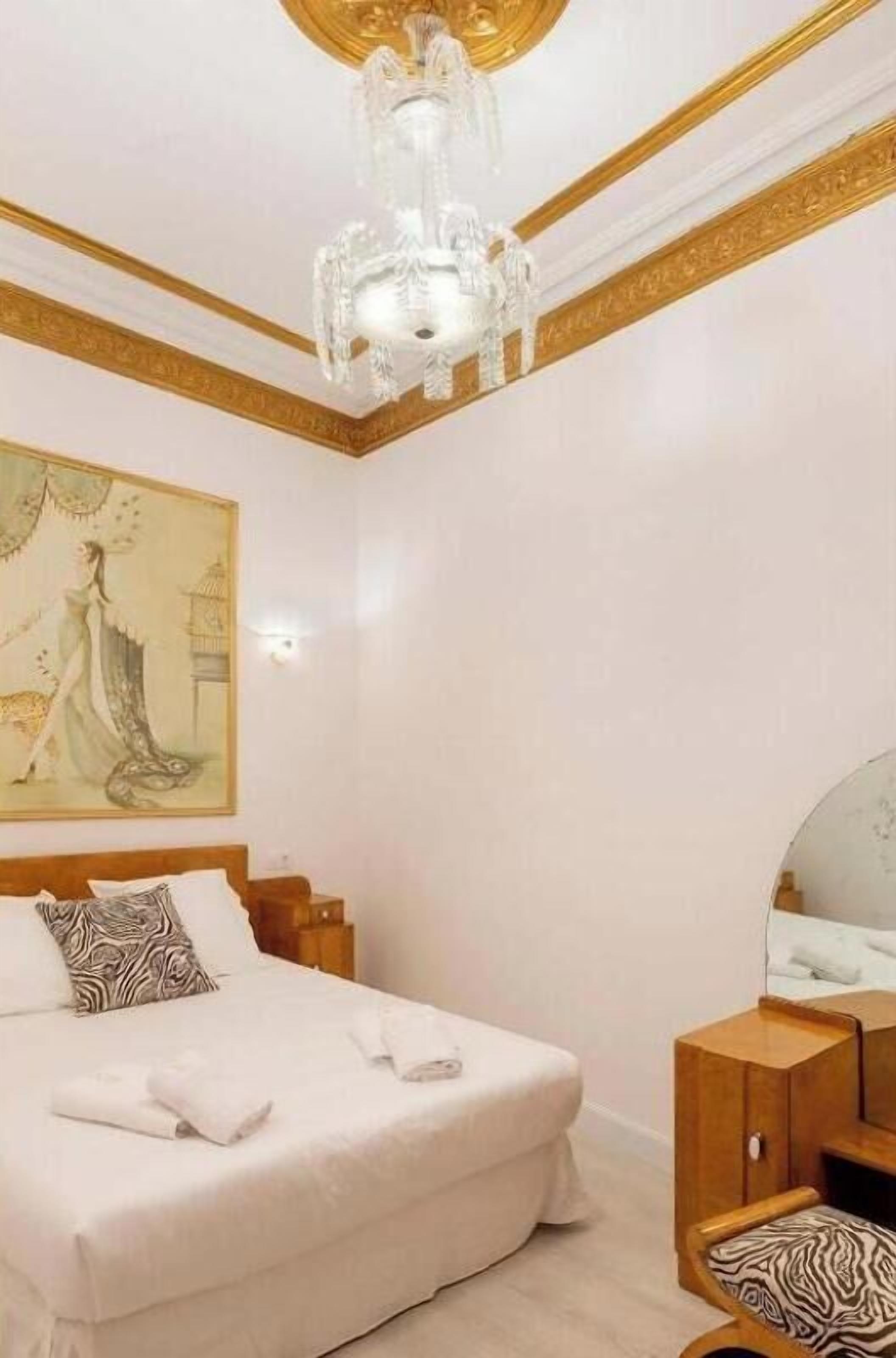 Ein Schlafzimmer mit einem großen Bett, einer Holzkommode, einem Spiegel und einer Deckenleuchte.