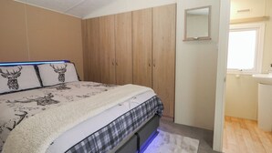 Ein Schlafzimmer mit Bett, Holzschrank und Badezimmer mit Waschbecken.