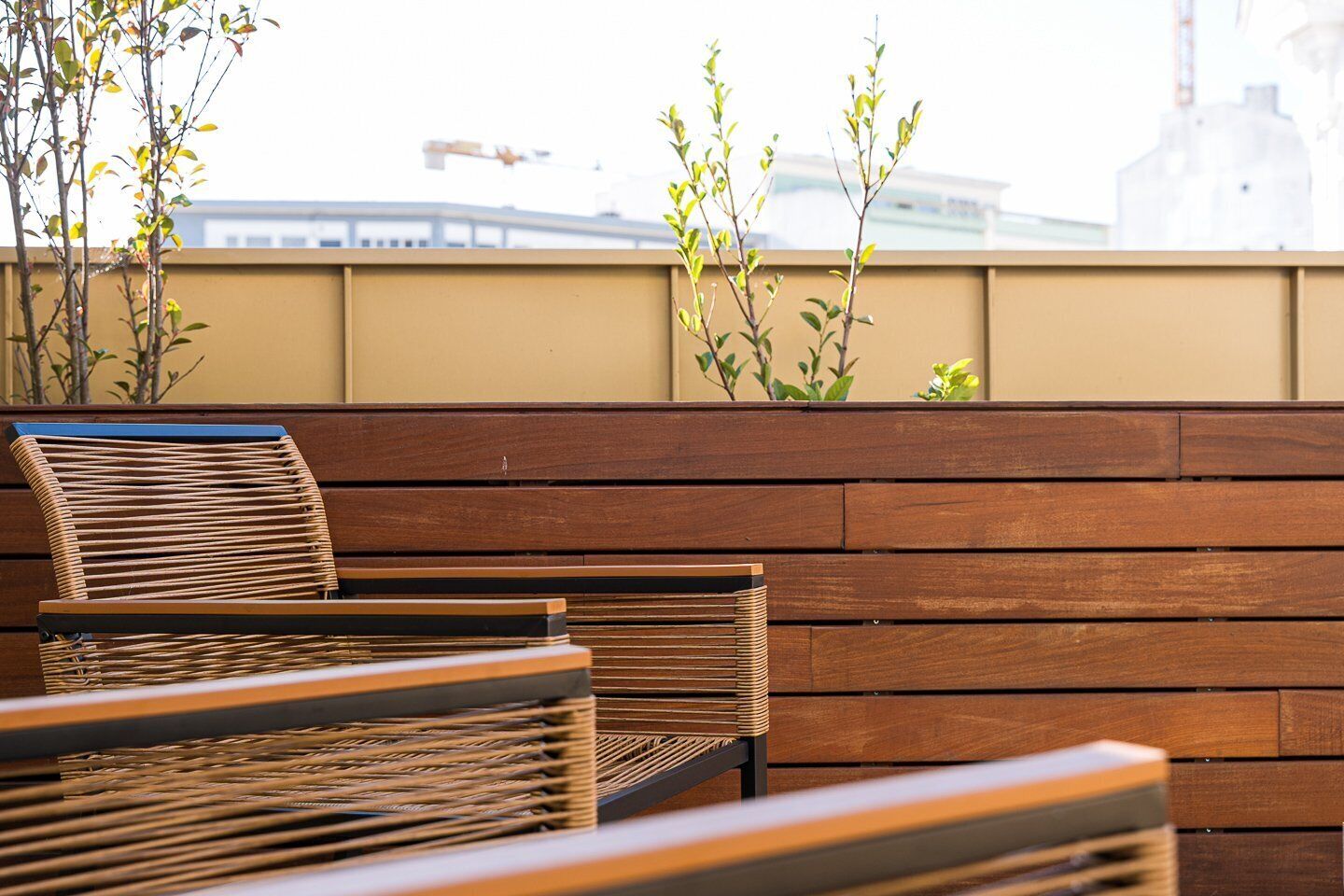 A wooden bench and chairs in an outdoor seating area with a view of a building in the background.