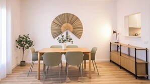 A dining area with a wooden table, six chairs, a decorative wall piece, a potted plant, and a built-in wooden cabinet. - 63IND1125- Brand new apartment (Barcelona)