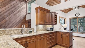 A kitchen with wooden cabinets, granite countertops, and a large window. - Ridgepoint Townhome 090 (Beaver Creek)