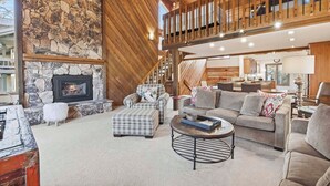 A cozy living room with a stone fireplace, a high wooden ceiling, and a comfortable seating area. - Ridgepoint Townhome 090 (Beaver Creek)