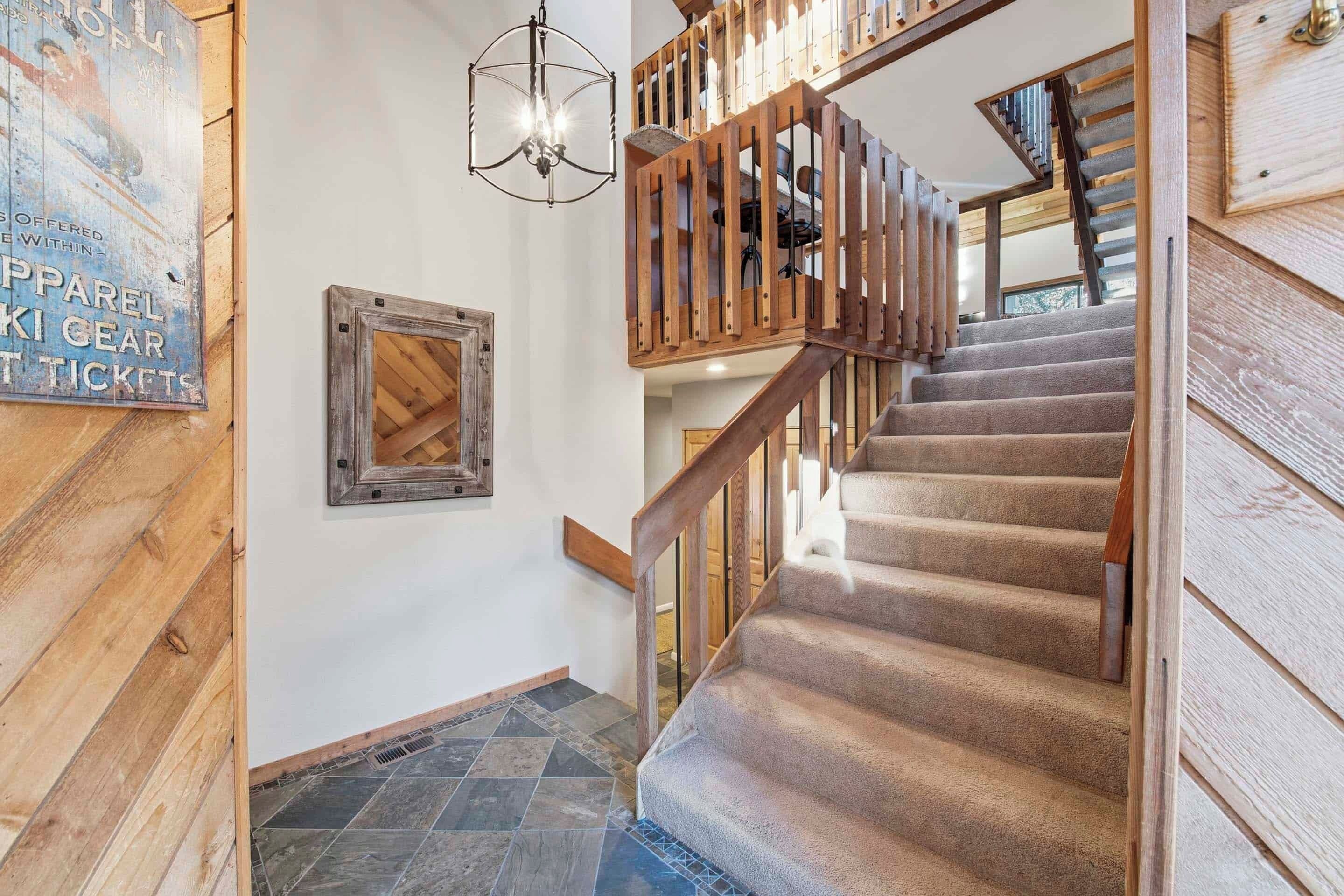 A wooden staircase with a wooden railing and a light fixture above it.