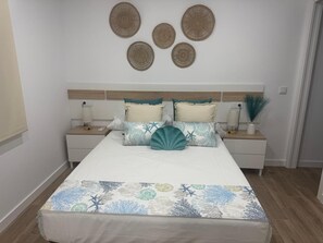 A bedroom with a bed, nightstands, decorative wall art, and a patterned bedspread. - Apartment 'Bajo De Guía - Bajo A' with Wi-Fi and Air Conditioning (Sanlúcar de Barrameda)