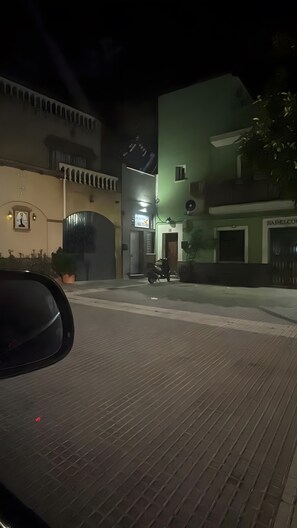 A nighttime street view with a parked motorcycle, a building with a sign, and a potted plant. - Apartment 'Bajo De Guía - Bajo A' with Wi-Fi and Air Conditioning (Sanlúcar de Barrameda)