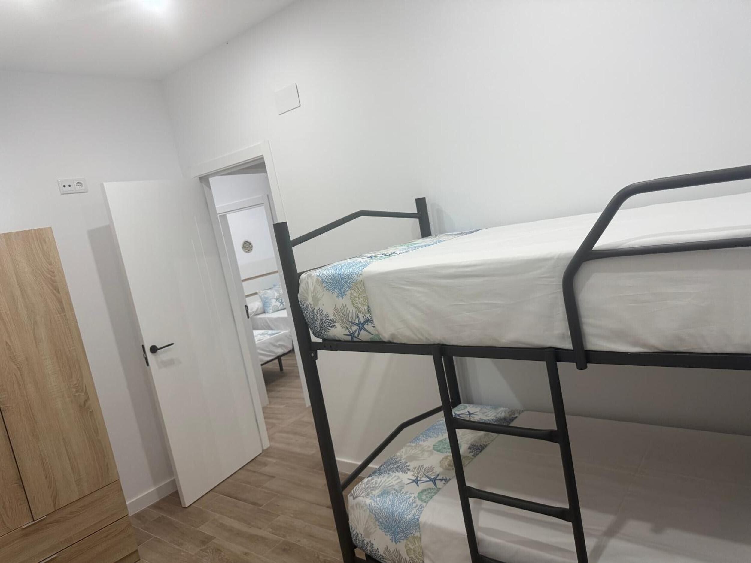 Habitación con literas, una puerta de madera y una pared blanca.