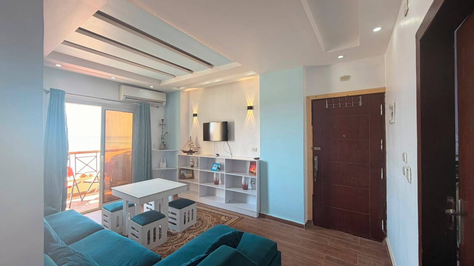 A modern living room with a sofa, a small table, and a TV mounted on the wall.