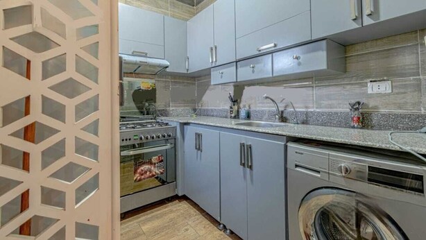A kitchen with grey cabinets, a stainless steel stove, and a washing machine. - Casablanca resort Hurghada Red Sea (Hurghada)