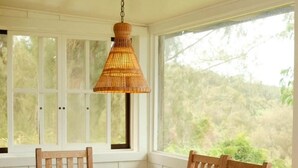 A wooden dining table with chairs in a room with large windows.