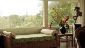 A cozy room with a wicker sofa, a small table with a vase of flowers, and a statue.