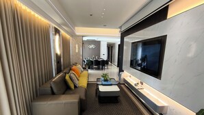 Ein modernes Wohnzimmer mit einer Couch, einem Couchtisch und einem an der Wand befestigten Flachbildfernseher.