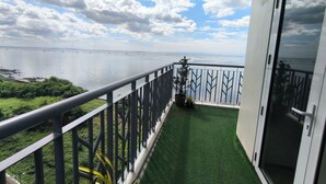 Ein Balkon mit Blick auf das Meer und eine Rasenfläche.