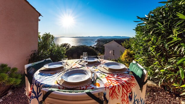 A table set outdoors with plates, glasses, and a woven placemat. - Boulouris Panorama - Vue sur la Mer (Saint Raphael)