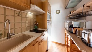 A compact kitchen with wooden cabinets, a stainless steel sink, a microwave, and a toaster. - Boulouris Panorama - Vue sur la Mer (Saint Raphael)