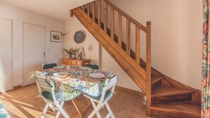 A dining area with a wooden staircase, a table set with plates and glasses, and a decorative wall piece. - Boulouris Panorama - Vue sur la Mer (Saint Raphael)