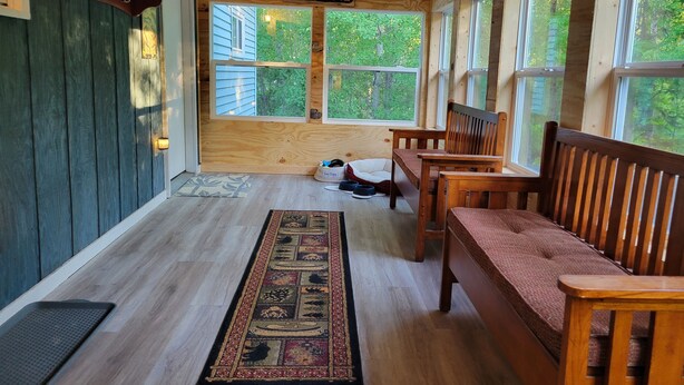 A wooden interior with a 'WELCOME' sign, a bench, a rug, and a dog bed. - Near lakes/rivers, town, snowmobile trails and access to hunting and state land. (Grayling)