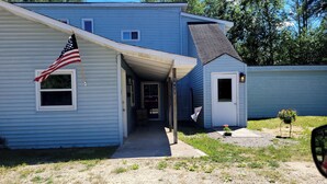 A blue house with an American flag, a small porch, and a mailbox. - Near lakes/rivers, town, snowmobile trails and access to hunting and state land. (Grayling)