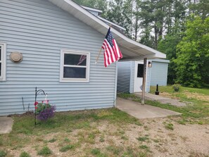 A light blue house with an American flag, a mailbox, and a small shed. - Near lakes/rivers, town, snowmobile trails and access to hunting and state land. (Grayling)