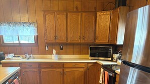 A kitchen with wooden cabinets, a stainless steel refrigerator, and a microwave. - Near lakes/rivers, town, snowmobile trails and access to hunting and state land. (Grayling)