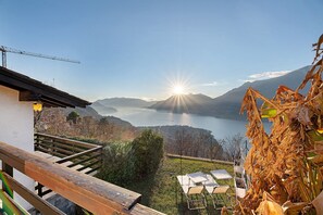 Une terrasse offrant une vue sur un lac et des montagnes, avec des meubles en bois et une grue de construction.