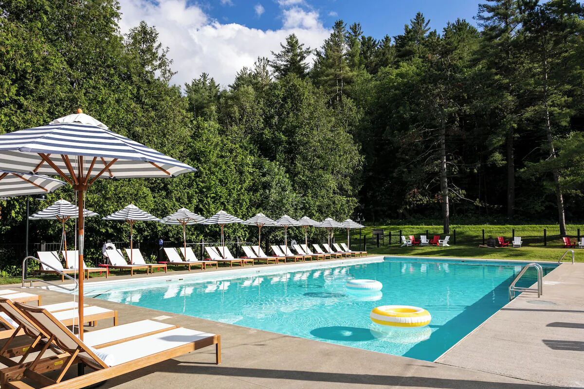 Dive into sunlit serenity with loungers and forest views.