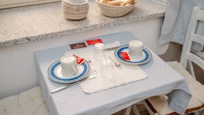 Een ontbijtje met een tafel, borden, kopjes en een mand met brood op een vensterbank.