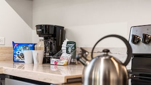 Eine Küche mit Kaffeemaschine, Wasserkocher und verschiedenen verpackten Lebensmitteln auf der Arbeitsfläche.