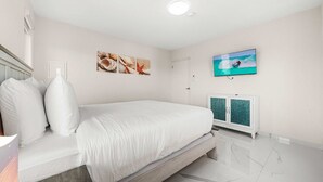 Ein Schlafzimmer mit einem Bett, einem an der Wand montierten Fernseher und einem Schrank mit grüner Tür.