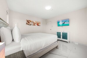 A bedroom with a bed, a television mounted on the wall, and a cabinet with a green door. - Prime location • Private pool & BBQ (Noord)