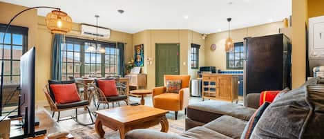 A living room with a sofa, armchairs, a coffee table, a television, and a ceiling fan.