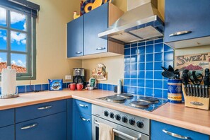 A kitchen with blue cabinets, a stove, and various kitchen items on the counter. - Charming 2 BR Condo with 2 Community pools! (Noord)