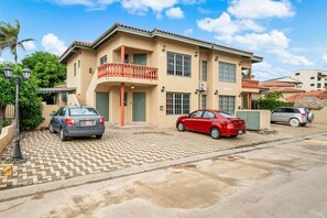 A two-story building with a balcony, parked cars, and a paved driveway. - 2BR Condo w/ 2 Community Pools, near Palm Beach (Noord)