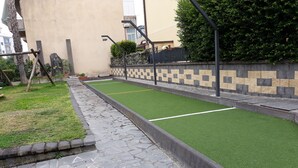 Pátio com gramado verde, caminho de pedra e parede com desenho ornamental.