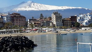 Uma cidade costeira com edifícios, uma praia de areia e uma montanha ao fundo.