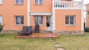 Ein zweistöckiges Gebäude mit Balkon, einer Glastür und einer kleinen Terrasse mit zwei Stühlen und einem Tisch.
