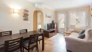 Ein Wohnzimmer mit Sofa, Fernseher und Essbereich mit Stühlen und Tisch.