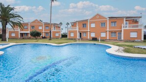 Ein Pool mit geschwungener Kante, umgeben von Gebäuden mit Balkonen und einer Palme.