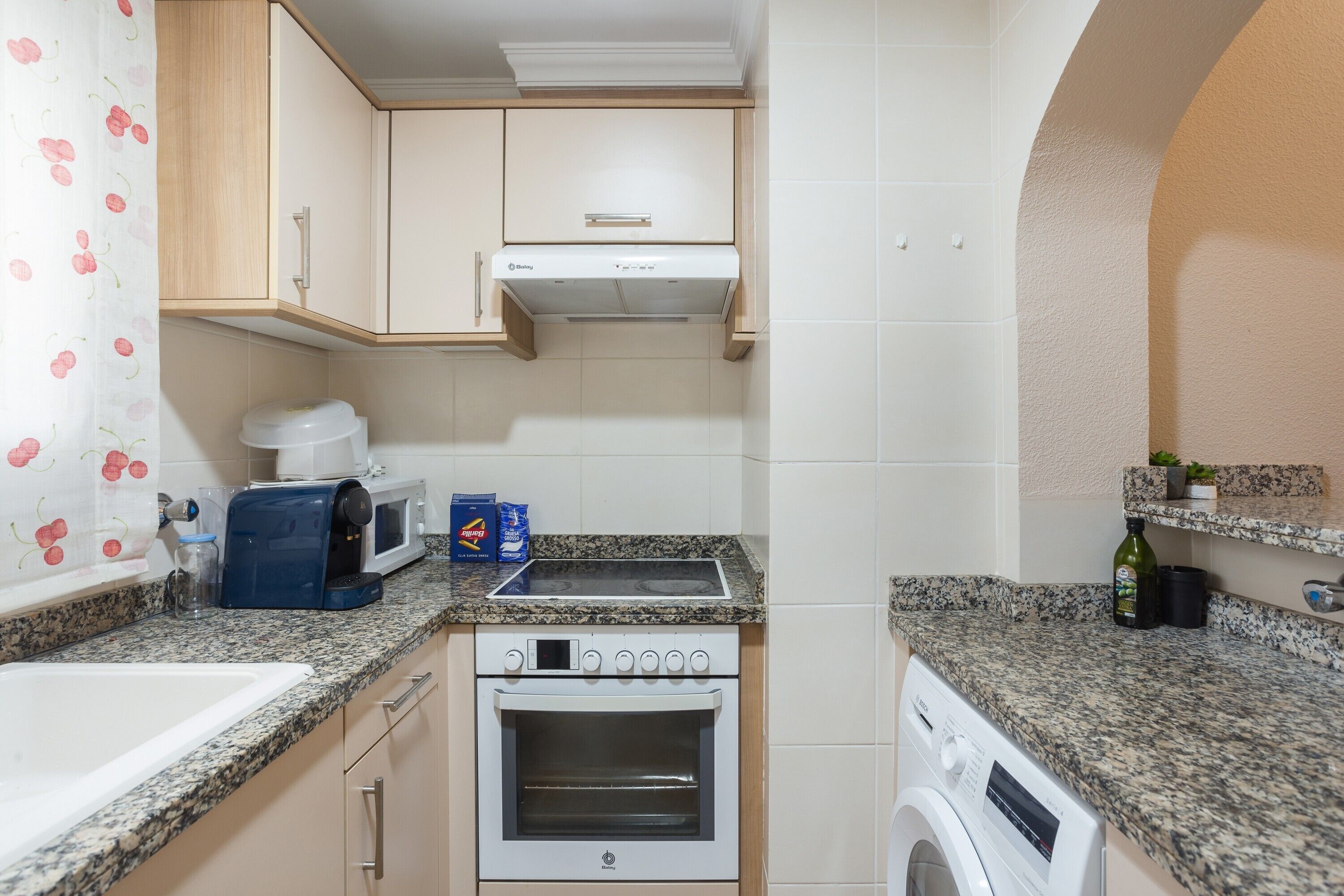 Eine kleine Küche mit Mikrowelle, Toaster, Backofen und Waschmaschine.