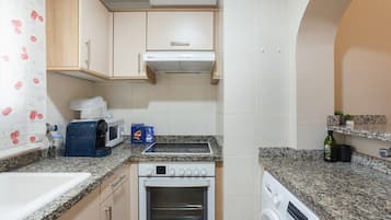 Eine kleine Küche mit Mikrowelle, Toaster, Backofen und Waschmaschine.