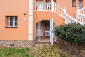 Un edificio con fondamenta in pietra, un cancello bianco e un piccolo giardino.